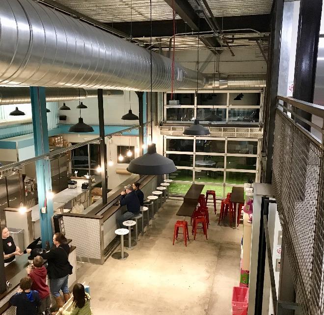 Bar and dining space with high ceilings and glass garage doors