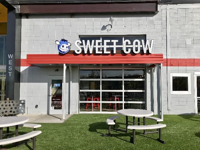 Retail storefront with glass sectional doors and outdoor seating area