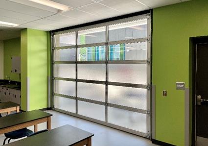 Classroom with aluminum full-view sectional door partially open for flexible layout