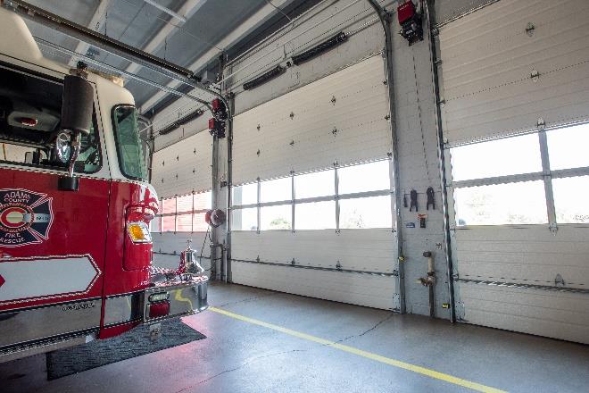 Fire truck inside station with full-view sectional doors allowing visibility