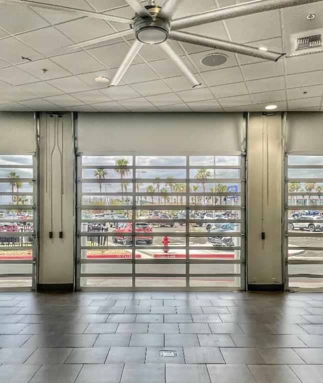 Interior vehicle delivery bay with insulated glass doors and ceiling fans