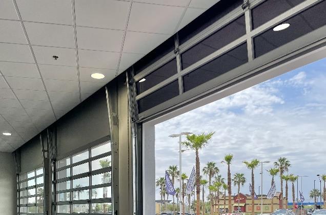Glass sectional doors partially open in dealership delivery area
