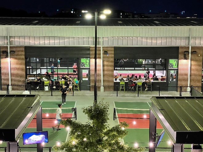 Outdoor pickleball courts with building featuring large glass doors