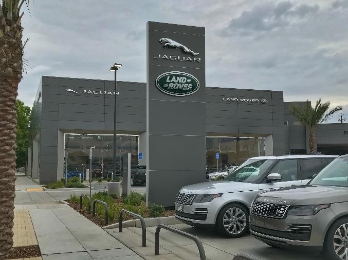 Auto dealership facade with glass garage doors and vehicle display