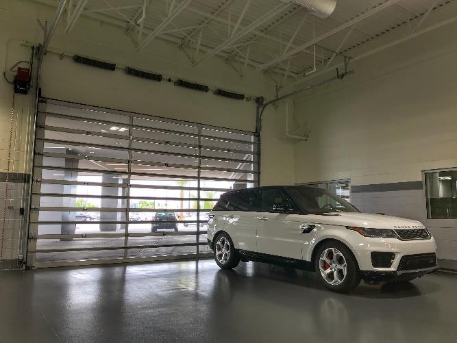 Service bay interior with vehicle and full-view glass garage door