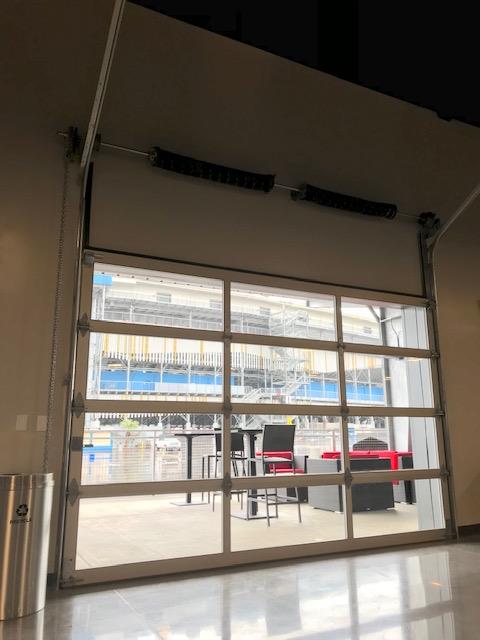 Glass sectional door providing visibility between indoor and outdoor spaces