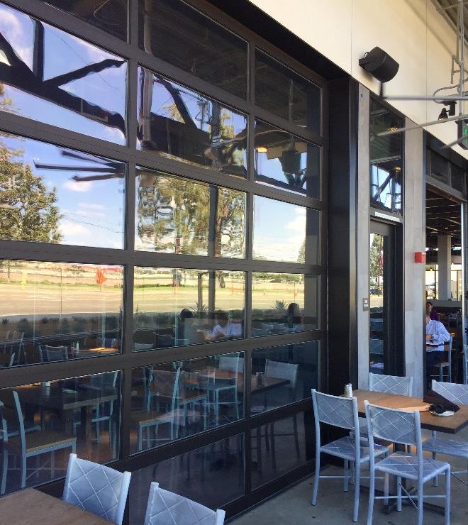 Full-view aluminum sectional door with dark bronze finish at brewpub