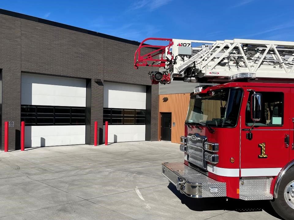 Fire station exterior with red fire truck and large sectional garage doors