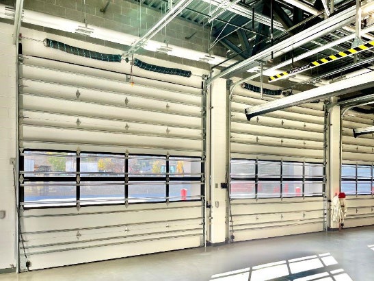 Fire station interior with multiple overhead doors and industrial ceiling systems