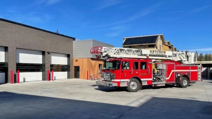 Fire truck parked outside fire station with large insulated garage doors