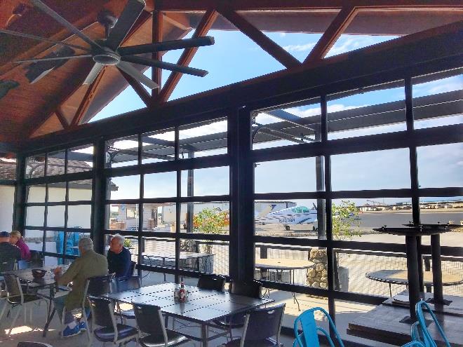 Restaurant interior patio with clear views of airplanes through glass doors