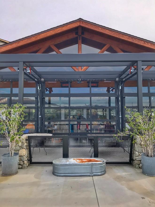 Glass sectional doors enclosing café patio with pergola and modern design