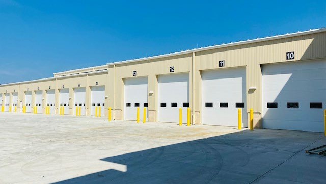Large utility building with multiple truck bay doors and yellow safety bollards