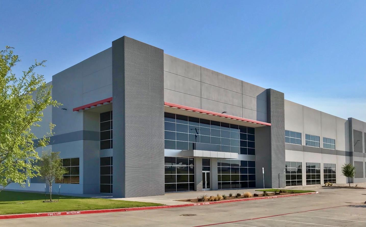 Modern industrial building facade with glass entrance and landscaping