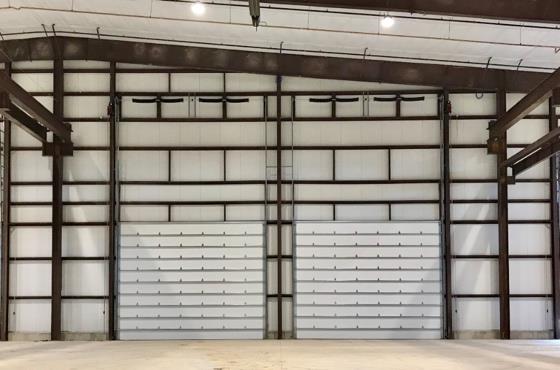 Large industrial steel sectional door inside manufacturing facility