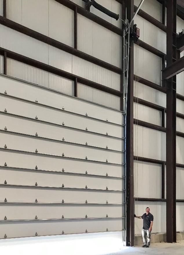 Extra-large industrial door with worker for scale in manufacturing facility