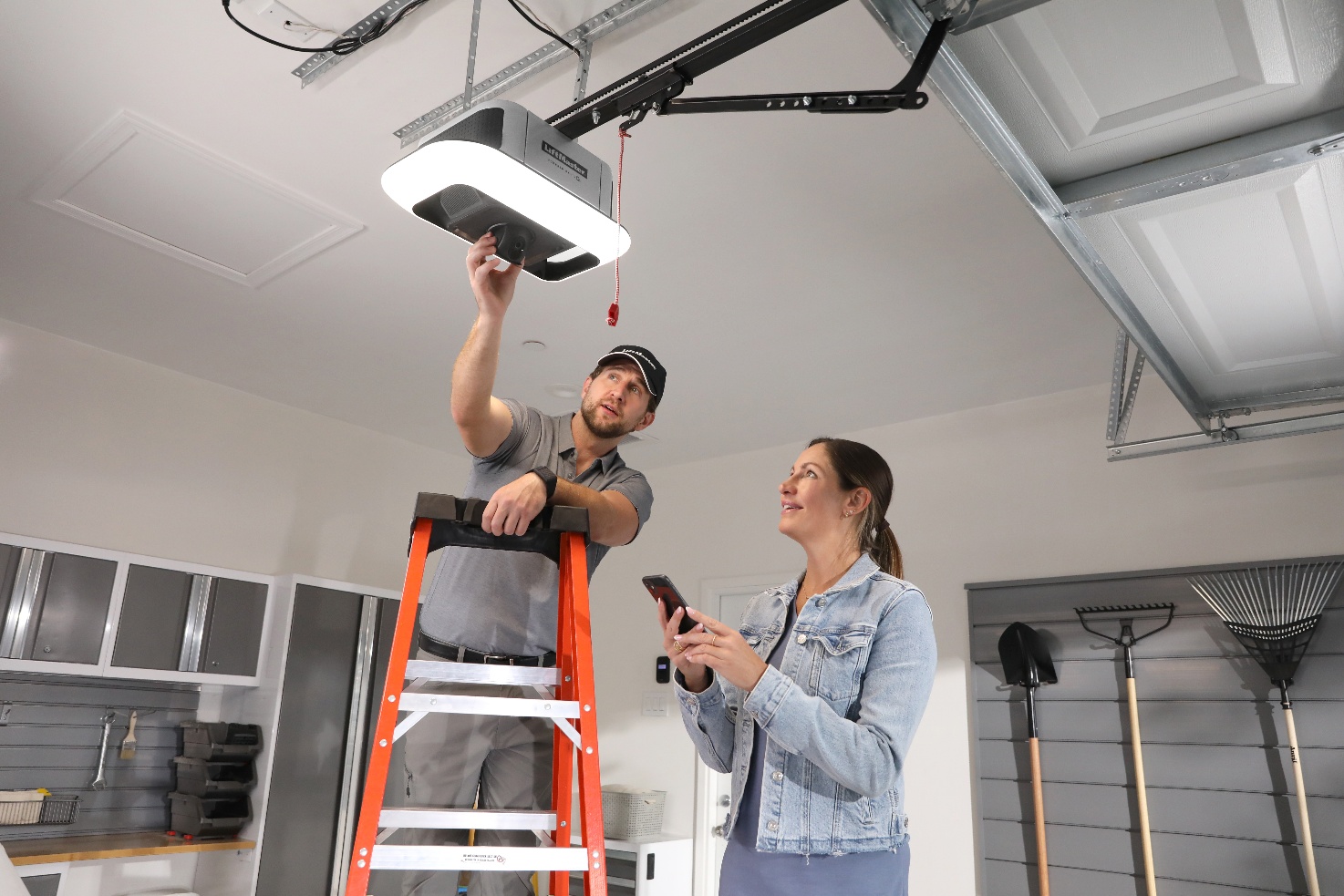 Hero lifestyle shot  LiftMaster opener in finished garage, homeowner on myQ app